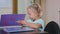 Little cute girl enters in classroom sits at the table and begins to study