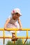 Little cute girl in hat climbs on children playground