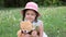 A little cute girl in a hat playing with her teddy bear. baby and favorite toy. summer, green glade.