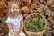 Little cute girl and a hedgehog. Nature surrounds the child. Composition of logs and basket. Friendship with a pet.