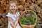 Little cute girl and a hedgehog. Nature surrounds the child. Composition of logs and basket. Friendship with a pet.