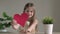 Little cute girl holding big red paper heart and sending air kiss