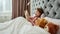A little cute girl holding her book closely and enjoying reading aloud while lying in a big bed with her teddybears in a