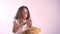 Little cute girl hugging her plush teddy bear, kid embracing toy, standing isolated on bright pink studio background