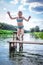 Little cute girl jumping off the dock into a beautiful river at