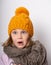 Little cute girl in a knitted hat and warm scarf looks surprised in shock