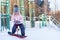 little cute girl learning to ride a children's snowboard, winter sports for the child, safety of active sports