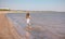 Little cute girl with lond hair in beautiful dress running on sea beach during summer holiday.Child playing on ocean beach. Sea