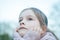 A little cute girl with long hair is sitting in a park seriously sad