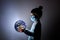 Little cute girl in medical mask holding a luminous planet Earth in her hands. Elements of this image furnished by NASA