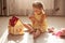 Little cute girl playing with her small kitty while sitting on floor in nursery. Children play with wooden toy house. Toddler kid