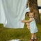 Little cute girl playing with laundry outside on