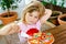 Little cute girl playing with wooden toy pizza. Preschool child having fun with children activity like, play with food