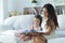 Little cute girl reading book with mother while sitting on safe