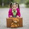 Little cute girl on the road with a suitcase