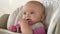 Little cute girl sits behind a children`s chair and plays with spoon.