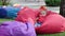 Little cute girl sits on the large soft garden chair on playground in the park. Slow motion