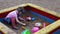 Little cute girl sits and plays with toys in sandbox