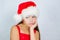 little cute girl is standing in a Christmas hat is sad