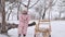 Little cute girl standing and eating Christmas gingerbread in snowy winter park. Cute baby wears warm pink fashionable