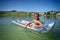 A little cute girl in a swimsuit swims on an inflatable mattress on a blue career lake