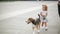 Little cute girl walks with her beagle dog across the city square keeping pet on leash.