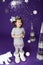 Little cute girl in white winter wreath and with toy polar bear having fun in studio on purple background with silver Christmas