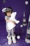 Little cute girl in white winter wreath and with toy polar bear having fun in studio on purple background with silver Christmas