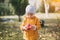 Little cute girl in a yellow jacket collects red apples