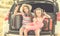 Little cute girls in the trunk of a car with suitcases