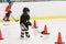 A little cute hockey girl is training on ice. Girl is wearing in full hockey equipment: helmet, gloves, skates. stick, puck. She i