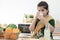 Little cute Indian kid girl holding and drinking a glass of milk for breakfast with crackers and fruits in kitchen at home