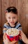 Little cute kid baby boy 2-3 years old , 3d cinema glasses holding bucket for popcorn, eating fast food on wooden background. Kids