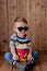 Little cute kid baby boy 2-3 years old , 3d cinema glasses holding bucket for popcorn, eating fast food on wooden background. Kids