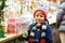 Little cute kid boy buying sweets from a cancy stand on Christmas market. Happy child on traditional family market in