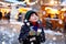 Little cute kid boy drinking hot children punch or chocolate on German Christmas market. Happy child on traditional