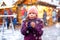 Little cute kid girl with cup of steaming hot chocolate or children punch. Happy child on Christmas market in Germany