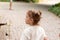 Little cute red-haired girl looks away in surprise while standing on a cobbled road