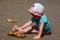 Little cute redhead child plays with sand on Bali beach