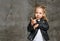 Little cute smiling blond girl in stylish rock style black leather jacket, jeans and white sneakers standing in confident pose
