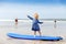 Little cute toddler girl at the Ballybunion surfer beach, having fun on surfboard for the first time, west coast of