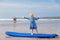 Little cute toddler girl at the Ballybunion surfer beach, having fun on surfboard for the first time, west coast of