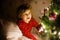 Little cute toddler girl in bed under Christmas tree and dreaming of Santa at home, indoors. Traditional Christian