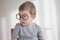 Little cute toddler preschooler boy in glasses with book looking straight at camera. Back to school concept
