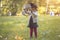 Little cute witch flips a basket and pours autumn leaves in the park