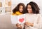 Little Daughter Congratulating Mom Giving Greeting Card Sitting On Couch