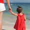 Little daughter holding moms hand watching sea