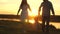 Little daughter holds mom and dad by the hands and jumps on the beach in the yellow sun. Family happiness. healthy baby