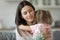 Little daughter hug young mom presenting flowers