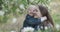 Little daughter hugs her mother and laughs. Mom with child in park with flowering trees.